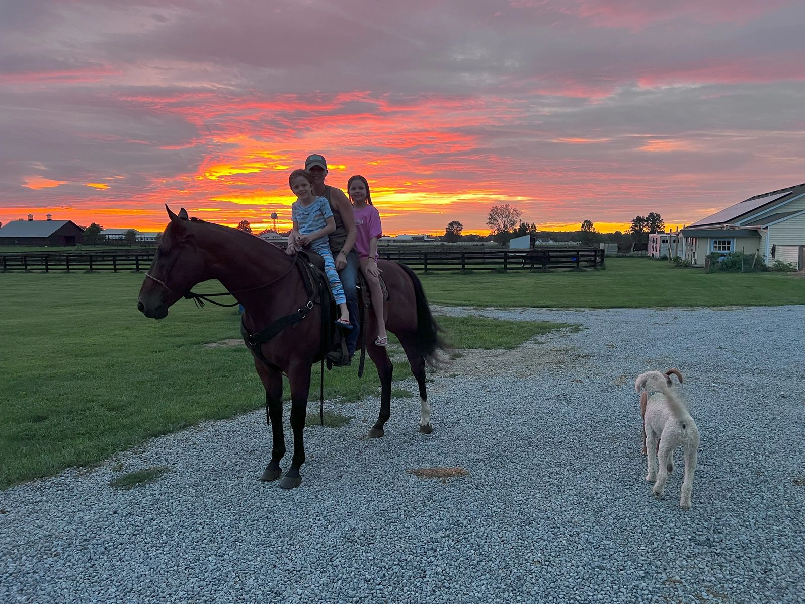 A family riding together at sunset with the farm dog nearby